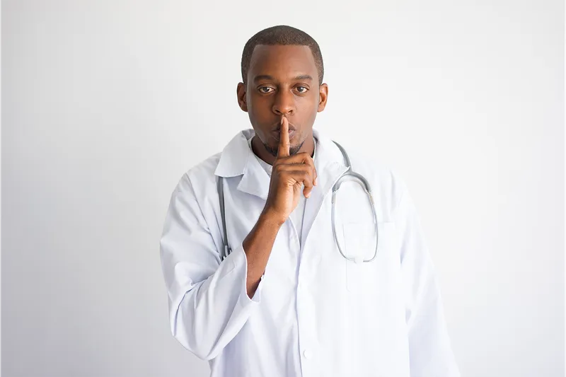 Doctor with finger to lips, symbolizing confidentiality