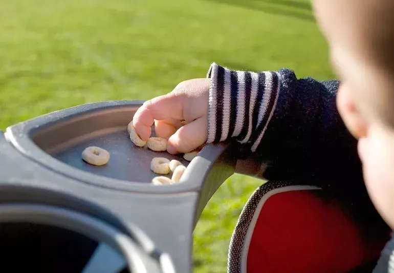 Infant using immature palmar grasp to pick up cereal