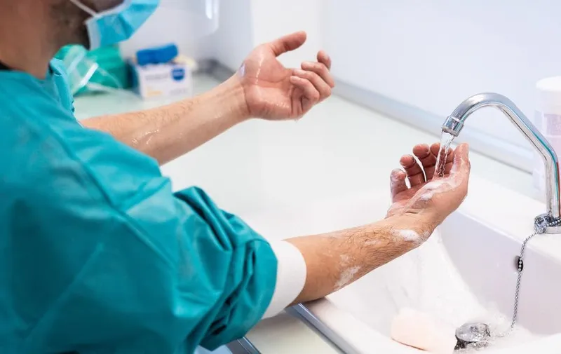 Healthcare worker performing hand hygiene at hospital sink