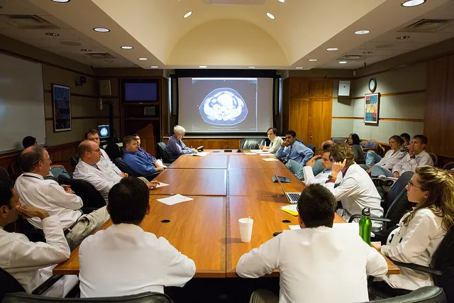 Multidisciplinary tumor board meeting with specialists reviewing cases